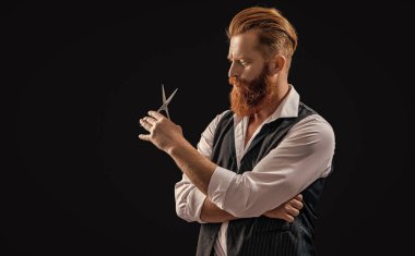 Stüdyo reklamındaki kuaför. Makas tutan kuaför. Arka planda kuaför adamın fotoğrafı var. Siyah giysili kuaför..