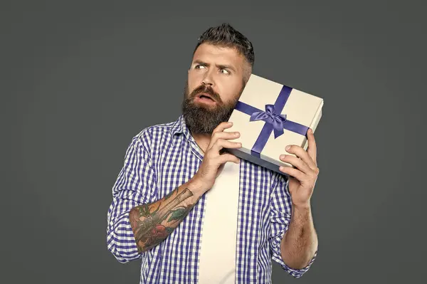 stock image mature bearded hipster with present box on grey background.