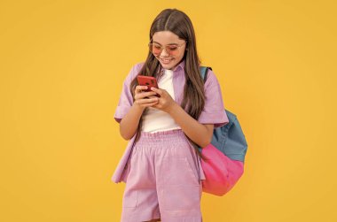 Genç kız sohbeti sarı renkte izole edilmiş. Stüdyoda liseli kız sohbeti. Genç kız sohbetleri arka planda. Liseli kızların telefonla sohbet ederken çekilmiş bir fotoğrafı..