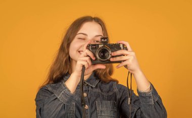 Mutlu genç kız fotoğrafçı kamera sarısı arka plana bakıyor, fotoğraf çekiyor..