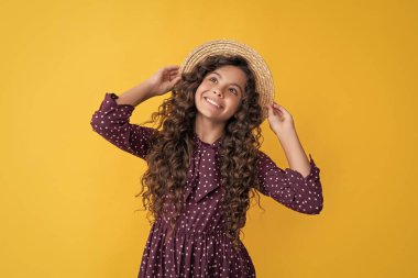 Sarı arka planda uzun kıvırcık saçlı, hasır şapkalı çocuk gülüşü..