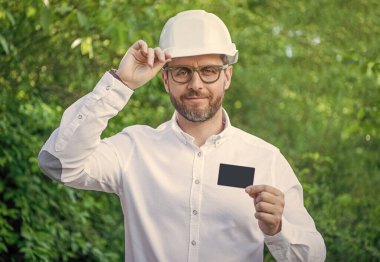 Kask takan işçi açık havada iletişim kartı gösteriyor, boşluğu kopyala.