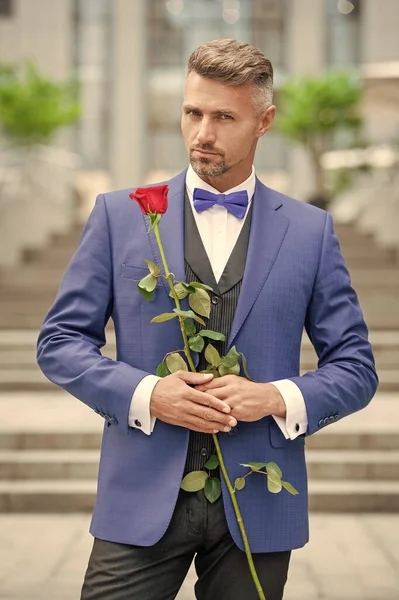 elegant man in tuxedo at romantic occasion. man with romantic present. dating romantic man with rose.