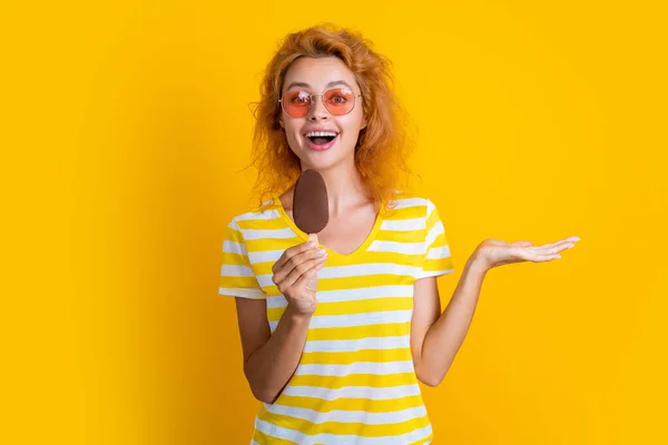 stock image girl with icecream in studio, presenting product. girl with icecream on background. photo of girl with icecream at summer. girl with icecream isolated on yellow.