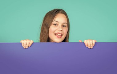 Boş mavi kağıdın arkasında reklam için fotokopi alanı olan neşeli bir çocuk..