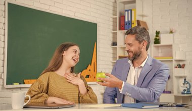 Sınıfta, özel öğretmeniyle elma paylaşan mutlu bir çocuk..