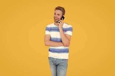 Gülümseyen adam stüdyoda telefonla konuşuyor. Adam ailesi ve arkadaşlarıyla konuşmak için telefonunu kullanıyor. Telefonla konuşan bir adam. Telefonla konuşan adam sarıda izole edilmiş..