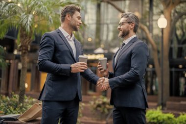 Pazarlık yapan iki iş ortağının fotoğrafı. Pazarlık yapan iki iş ortağı. İki iş ortağı açık havada pazarlık yapıyor. Kahve dağıtan iki iş ortağı.