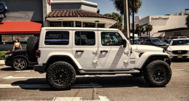 Miami, Florida ABD - 25 Mart 2023: beyaz 2018 Jeep Wrangler Sınırsız Sahra arabası yolda, yan görüş.