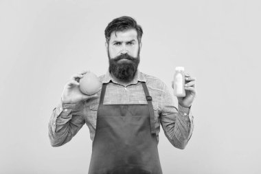 Elinde turuncu ve meyve suyu şişesi olan ciddi bir adam sarı arka planda, barmen..