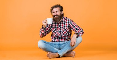 Kareli gömlekli, modaya uygun saç stili olan beyaz bir hippi sabah kahvesi ya da fincandan çay içer, ilham verir..