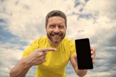 Gülümseyen adam akıllı telefon ekranını kopyalama alanı ile sunuyor.