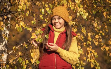 Sonbahar yapraklarıyla okul saatlerinde gülen genç bir çocuk..