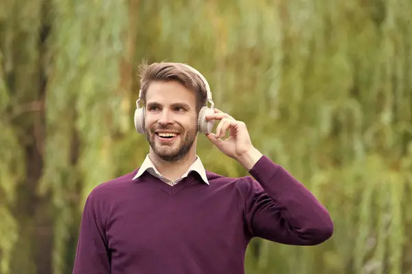 happy young handsome guy listen music in headphones outdoor.