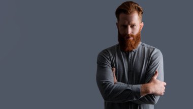 Gri arka planda sakallı ve bıyıklı traşsız adam, kopyalama alanı. Traşsız adamın stüdyo çekimi. Bıyık ve sakal bakımı. Tıraşsız yakışıklı adamın sakalı ve bıyığı var..