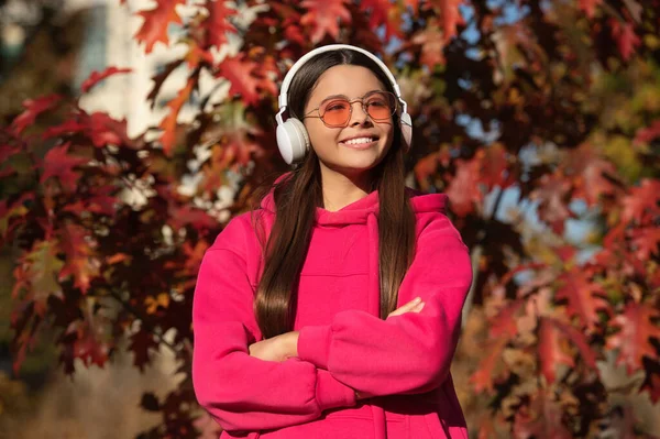 Autumn teen girl listen music in headphones during fall season in park outdoor.
