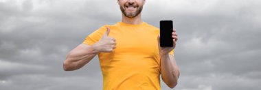 Kopya alanı olan akıllı telefonun reklamını yapan adamın kırpılmış görüntüsü.