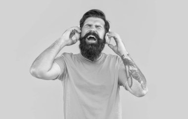 Müzik konseptini dinle. Kulaklıklı mutlu adamın stüdyo fotoğrafı. Havalı adam müzik dinler. Sakallı adam sarı arka planda izole edilmiş kulaklıkla müzik dinliyor. Adam kulaklıkla müzik dinliyor..