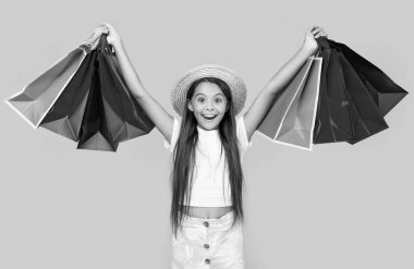 Sarı arka planda alışveriş torbaları olan hayret verici bir genç kız..