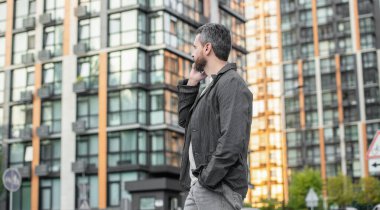 man has mobile call looking far outdoor. man having mobile call in the street. man call on mobile outside. photo of man call on mobile phone.