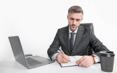 mature manager writing at the table in business office.