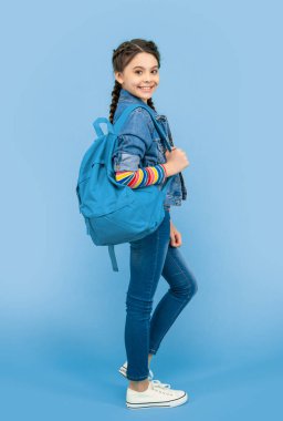 Happy teen girl holding school bag blue background. School education. Back to school.