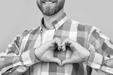 Kırpılmış sakallı beyaz gömlekli adam, sarı arka planda izole bir aşk kalbi olduğunu gösteriyor. Stüdyoda aşk dolu, sıradan bir beyaz adam. Aşkı gösteren bir adamın fotoğrafı. Aşkı işaret eden adam..