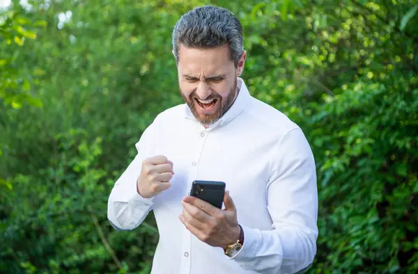 angry shouting marketing businessman with phone outdoor. marketing businessman with phone work online. photo of marketing businessman with phone. marketing businessman with phone.