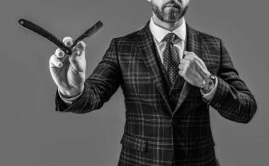 Traş bıçağıyla berber, seçici odaklanma. Berber stüdyosunda bıçaklı bir adam. Berber bıçaklı sakallı adamın fotoğrafı. Berber adam, gri arka planda bıçak tutuyor..