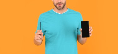 Sarı arka planda telefon ve stil sunan kırpık genç adam, sunum.