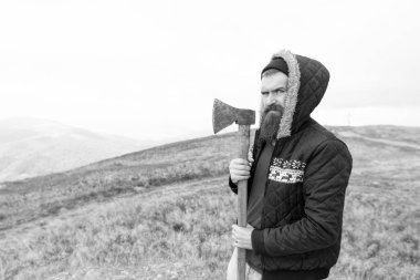 bearded man lumberjack hold axe outdoor, advertisement. bearded man lumberjack has axe. bearded man lumberjack with axe. photo of bearded man lumberjack holding axe in the mountain.