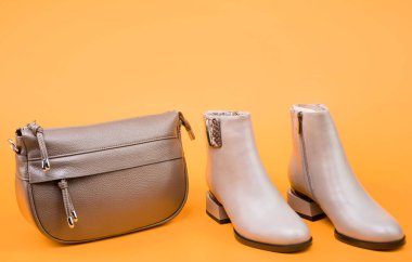 bej çizmeler. Sarı arka planda ayak bileği çizmeleri. Ayakkabı dükkanı. Alışveriş konsepti. Kadın derisi şık ayakkabılar. Moda aksesuarı. kopyalama alanı. Bir çift şık deri ayakkabı ve çanta..