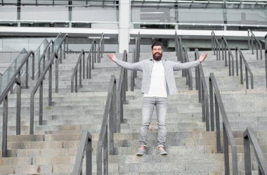 happy bearded man downstairs. full length of man with beard. hipster man outdoor at stairs.