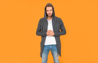 Kendine güvenen ve yakışıklı, tıraşsız adam. Erkek modası. Erkek güzelliği. Tüylü adam. Sarı arka planda sakallı genç bir adam. saç ve sakal bakımı.