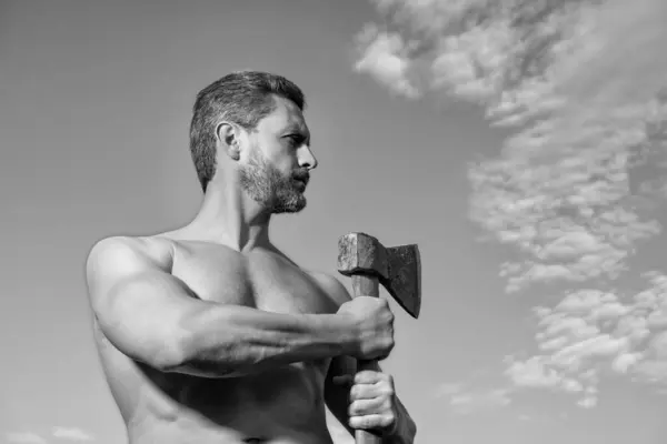 stock image shirtless man with axe. caucasian man hold ax. brutal man on sky background. copy space.