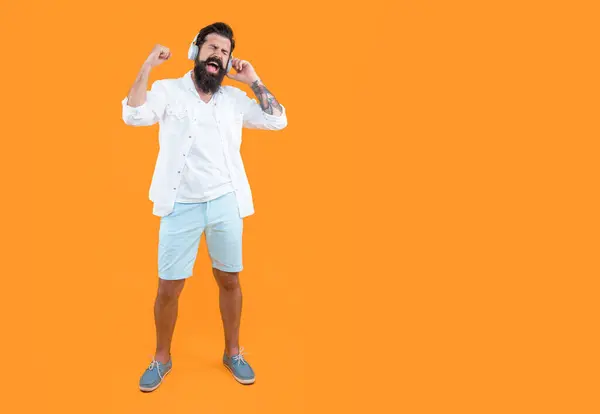 listen to music concept. studio shot of shouting man with headphones. cool man listening music. bearded man listening music in headphones isolated on yellow. man listening music in headphones.