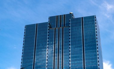 Camsı yüzlü bir gökdelen. Modern cam bina. Metropolis City 'de bir gökdelen. Şehir merkezinde gökdelenli bir şehir. İş yerindeki ofis binası. Gökdelen mimarisi. modern şehir.