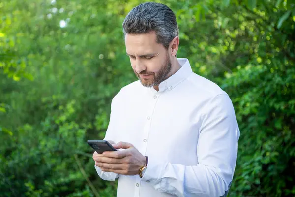 Neşeli pazarlama işadamı ve açık havada telefon. İnternette telefon işi yapan pazarlama işadamı. Telefonlu pazarlama işadamının fotoğrafı. Telefonlu pazarlama işadamı.