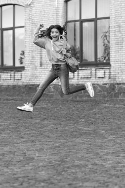 school girl jump childhood outside, college. school girl jump childhood at the street. photo of school girl jump childhood with backpack. school girl childhood jump outdoor.