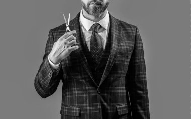 barber man with scissors. man with scissors in barber studio. photo of bearded man with barber scissors. barber man hold scissors isolated on grey background.