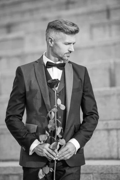 special occasion concept. caucasian man with rose for special occasion. tuxedo man outdoor at special occasion.