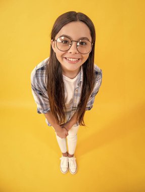 smiling teenager girl isolated on yellow. teenager girl in studio. teenager girl on background. photo of teenager girl with long hair wearing glasses.