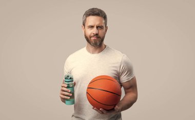 Sporcu basketbolcu adam topla su içer. Spor giyim sektöründe basketbolcu. Sporcu basketbolcu gri arka planda izole edilmiş. Stüdyoda sporcu basketbolcu.