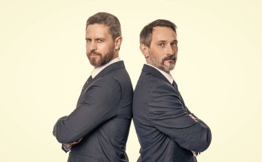 Lider iş adamları ortakları sırt sırta. Stüdyoda lider iş adamlarının liderliği. Lider iş adamları ortaklarının imajı takım elbise giyer. İki lider iş ortağı beyazlarda izole edildi