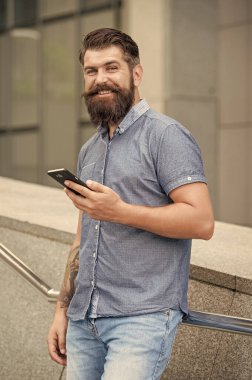 Cep telefonu kullanan sakallı adam. Dışarıda cep telefonu kullanan mutlu bir adam. Elinde cep telefonu tutan gülümseyen adam..