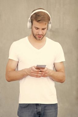 Yakışıklı adam mp3 müzik listesini beyaz gömlekle seçiyor. İnsan mp3 müzik listesinin kulaklıkla fotoğrafı. Adam mp3 müzik listesini açıyor. Adam dışarıda mp3 müzik listesi kullanıyor.