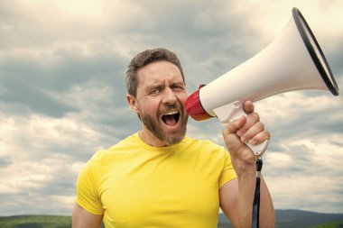 Sarı gömlekli adam arka planda hoparlörle bağır..