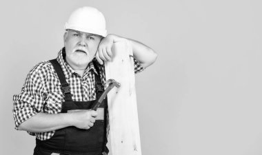 Sarı arka planda miğferli yaşlı bunak marangoz..