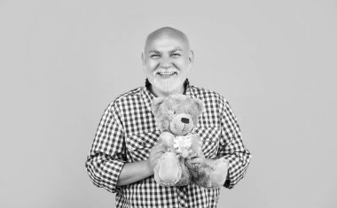 happy mature man in checkered shirt with toy on yellow background.