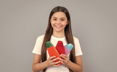 teen girl with shampoo cosmetics isolated on grey. teen girl with shampoo cosmetics in studio. teen girl with shampoo cosmetics on background. photo of teen girl with shampoo cosmetics.